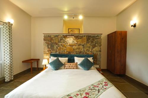 a bedroom with a large bed with a stone wall at Astroport Sariska Treetop by Eight Continents in Tehla