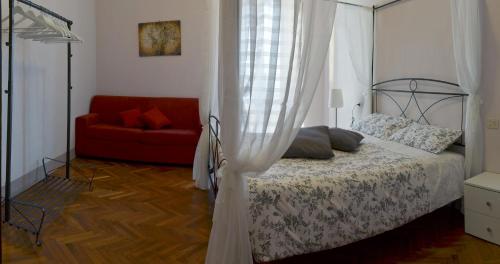 オッフィダにあるDimora nel borgoのベッドルーム(天蓋付きベッド1台、赤いソファ付)