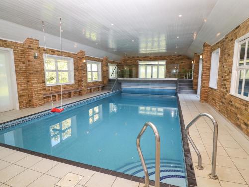 a large swimming pool with blue water in a building at Hall Farm in Market Rasen
