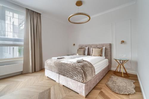 a white bedroom with a bed and a window at Apartament Gold LUX AIRCON in Szczecin