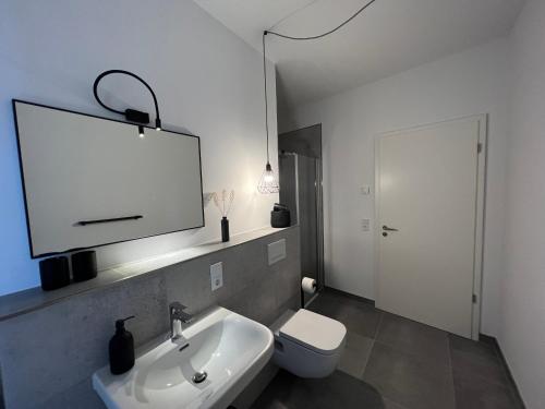 ein weißes Bad mit einem Waschbecken und einem WC in der Unterkunft Apartmenthaus Sassnitz Zum Stadthafen Apartment 2 in Sassnitz