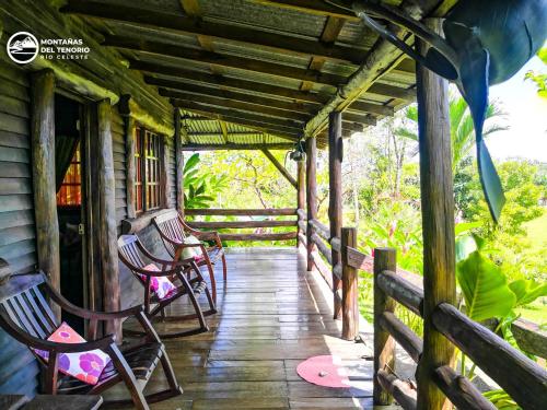 a porch of a house with chairs and a fence at Cabañas Montañas del Tenorio in San Rafael