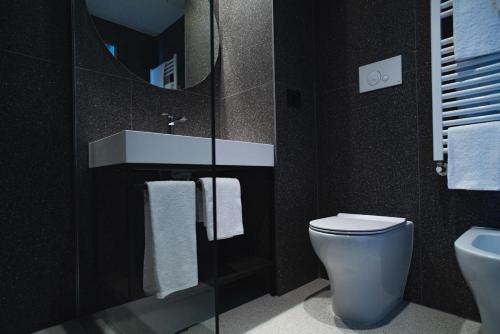 een badkamer met een toilet, een wastafel en een spiegel bij Hub Hotel in Gubbio