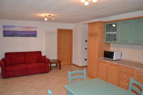 a living room with a red couch and a kitchen at Agritur Agribaldo Lavanda in Brentonico