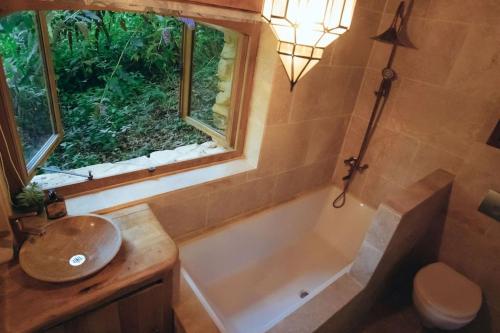 La salle de bains est pourvue d'une baignoire, d'un lavabo et d'une fenêtre. dans l'établissement Lake House I // Alauzet Ecolodge + Nature spa, à Castelnau-de-Mandailles