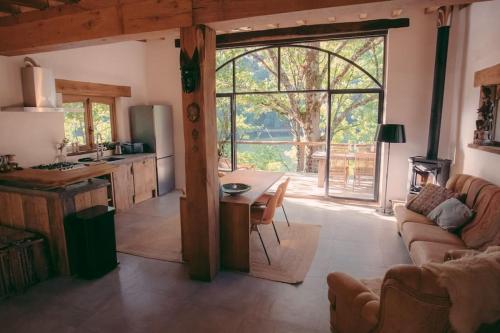 a kitchen and living room with a table and a couch at Lake House I // Alauzet Ecolodge + Nature spa in Castelnau-de-Mandailles
