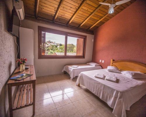 a bedroom with two beds and a window at Pousada do Mica in Praia do Rosa