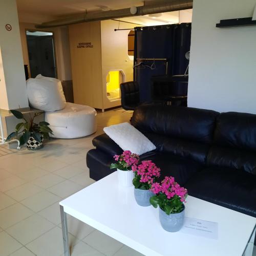 una sala de estar con sofá y flores en una mesa. en Wooden box with sleeping amenities Vindegade 53E, en Odense