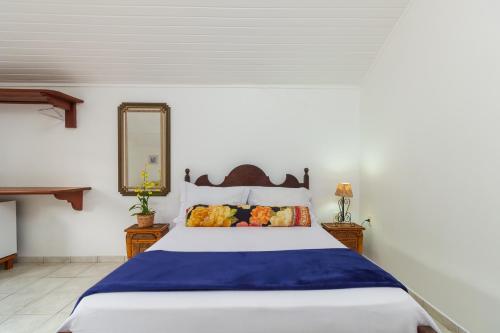 a bedroom with a blue and white bed and a mirror at Casa Aldeia Paraty in Paraty