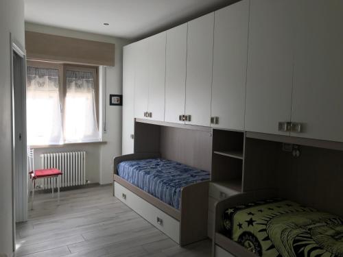 1 dormitorio con cama, armarios blancos y ventana en A CASA DI LETY, en Tarvisio