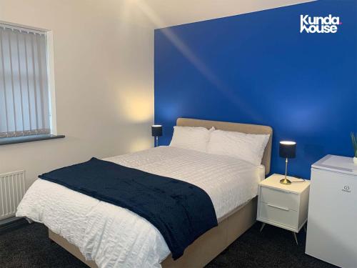 a bedroom with a king sized bed with a blue wall at Kunda House Seymour Oldbury in Oldbury