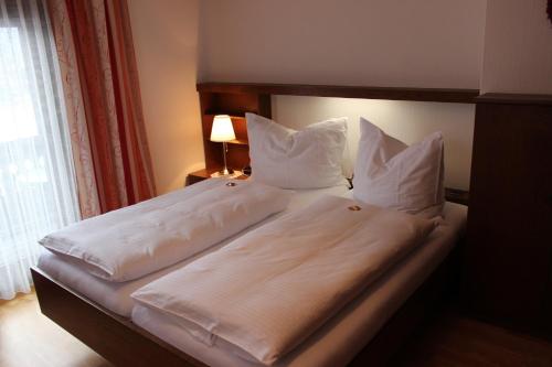 a bed with white sheets and pillows in a bedroom at Pension Wolfgangsee in St. Wolfgang