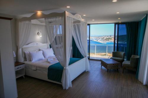 a bedroom with a canopy bed and a balcony at Aden Boutique Otel in Çeşme
