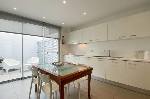 eine Küche mit einem Holztisch und weißen Schränken in der Unterkunft Casa do Mar South in Ponta Delgada