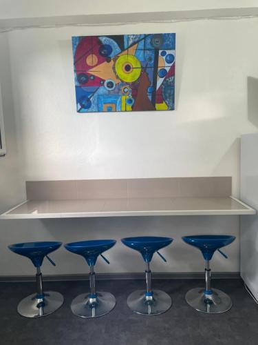a counter with four blue bar stools under a painting at La perle créole in Lamentin