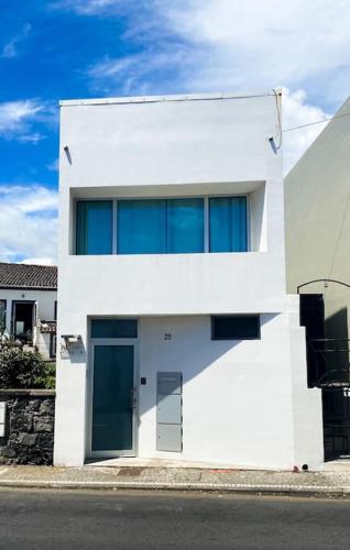 a white building with blue windows on a street at Casa do Mar South in Ponta Delgada