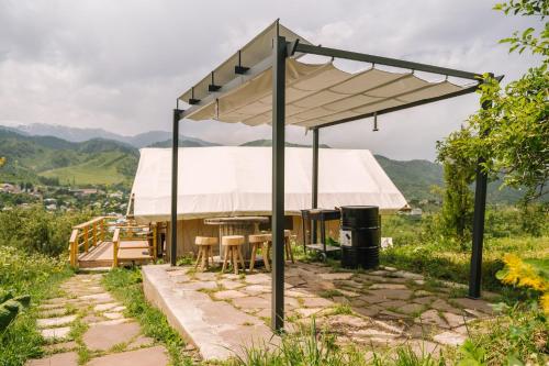 a pavilion with a table and chairs under a white tent at Гора Глэмпинг in Besqaynar