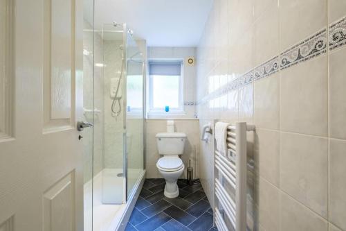 uma casa de banho com um WC e uma cabina de duche em vidro. em Monicas Apartment Lovely ground floor 2 bedroom serviced apartment em Coatbridge