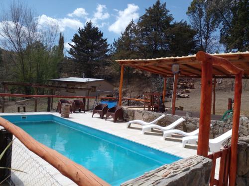 una piscina con terraza y sillas junto a ella en Cabañas "La Quimera" en El Durazno