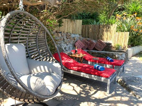 twee schommelstoelen en een vuurplaats in de achtertuin bij Home Suite Hout Bay in Kaapstad