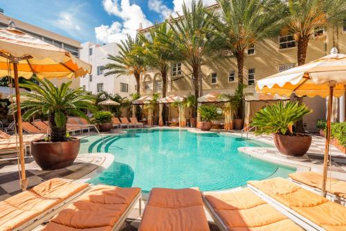 a large swimming pool with lounge chairs and umbrellas at The Plymouth South Beach in Miami Beach