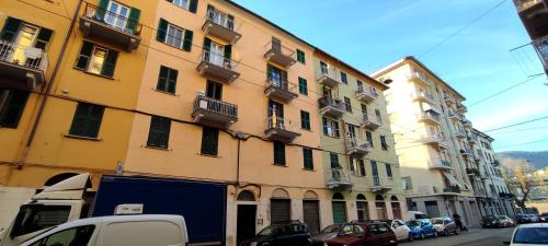 un grand bâtiment jaune avec des voitures garées devant lui dans l'établissement Mirdita - Casa Vacanze, à La Spezia