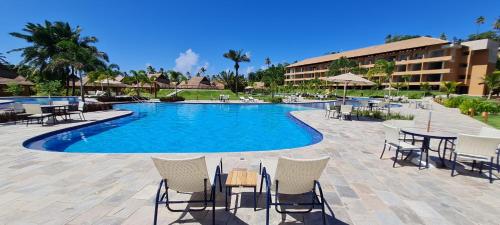 a swimming pool with tables and chairs in front of a hotel at Eco Resort - Pé na areia da Praia dos Carneiros in Praia dos Carneiros