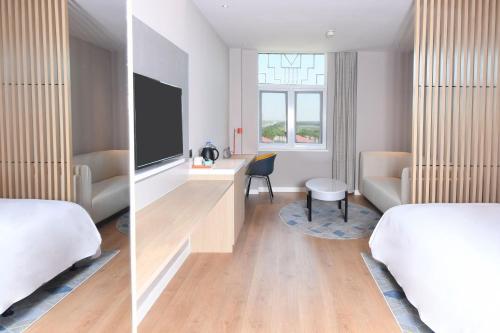 a hotel room with a bed and a tv at Holiday Inn Express Tianjin Binhai by IHG in Binhai
