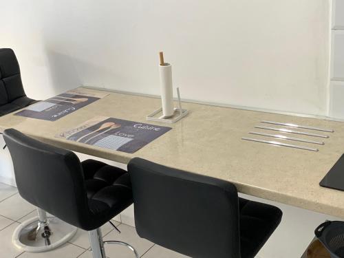 a counter with chairs and a table with a vase at TRANSIT AFFAIRES - LOISIRS in Pointe-à-Pitre