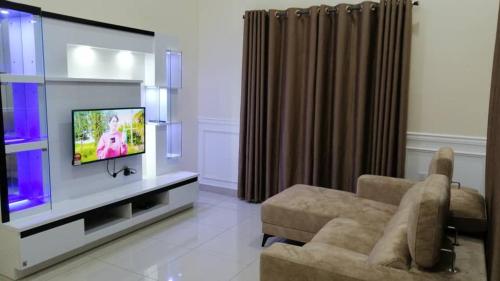 a living room with a tv and a couch at Homestay Sungai Besar with Private Pool RUMAH HANA in Sungai Besar