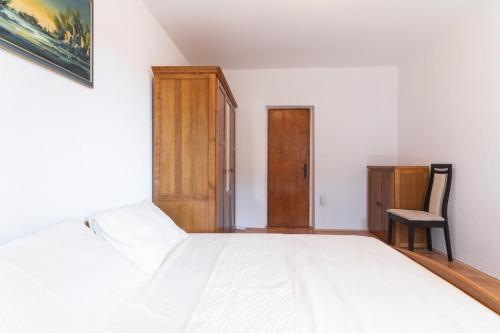 a bedroom with a white bed and a wooden cabinet at Beachfront apartments Calm Sea in Preko