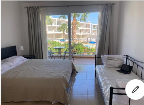 a bedroom with two beds and a view of a patio at Cyprus Studio with pool near Beach in Peyia