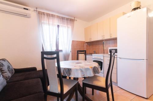 a kitchen with a table and chairs and a white refrigerator at Beachfront apartments Calm Sea in Preko