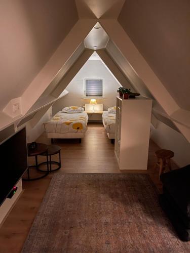 um quarto no sótão com 2 camas e uma televisão em ‘t Bakhuis em Oostelbeers