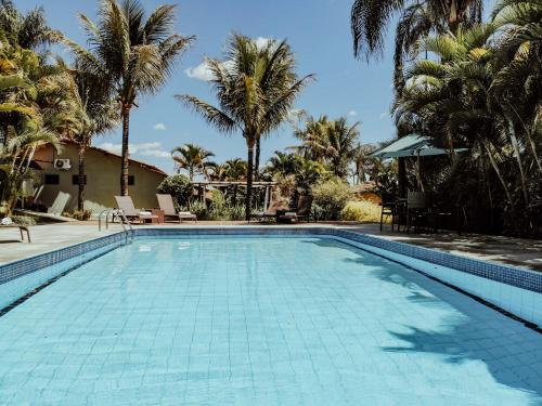 a swimming pool with palm trees in the background at Pousada Recanto da Grande Paz in Alto Paraíso de Goiás