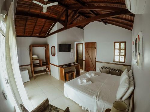um quarto com uma cama branca e uma televisão em Pousada Recanto da Grande Paz em Alto Paraíso de Goiás