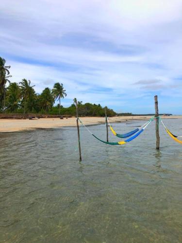 two hammocks on posts in the water near a beach at Pousada o Casarão in São Miguel dos Milagres