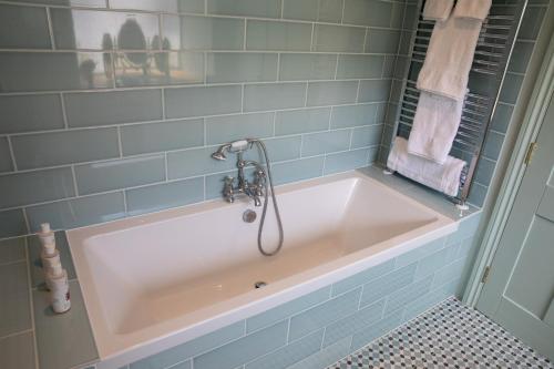 a bath tub in a bathroom with blue tiles at SEED Hub in Wincanton