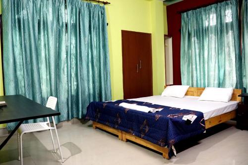 a bedroom with a bed and a table and curtains at Urbanica Homestay in Guwahati