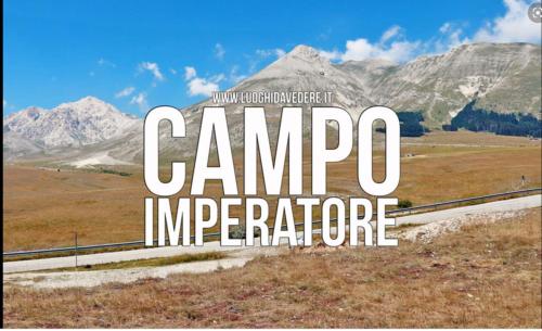 a sign that reads campo interpreter with mountains in the background at Appartamento nel cuore di Campo Imperatore in Castel del Monte