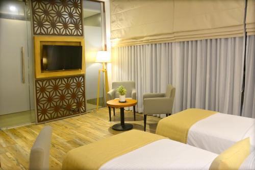 a hotel room with two beds and a chair and a television at Belmont Boutique Hotel - Free Airport Shuttle Service in Negombo