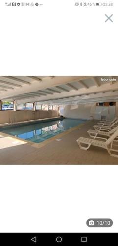 une piscine avec des chaises longues dans un immeuble dans l'établissement Auron, 2 pièces meublé, coin montagne,6 couchages, à Saint-Étienne-de-Tinée