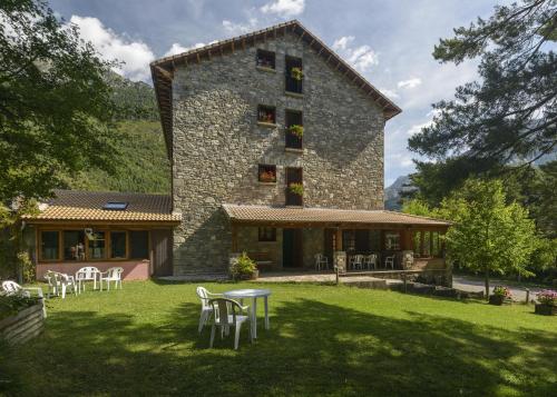 ein großes Steingebäude mit Tischen und Stühlen im Hof in der Unterkunft Hotel de Montaña Uson in Hecho
