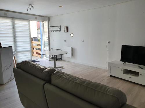 a living room with a couch and a table and a tv at Flobart grand appartement à Sangatte au rdc et à 30 metres de la plage in Sangatte