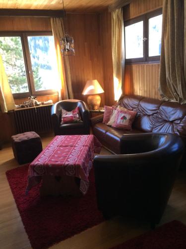 a living room with a leather couch and a table at Chalet-Hôtel du Borderan in La Clusaz
