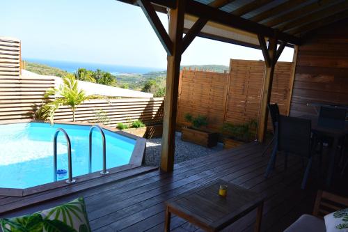 una terraza con piscina y mesa en Maison Piscine personnelle vue mer COSY en Le Marin