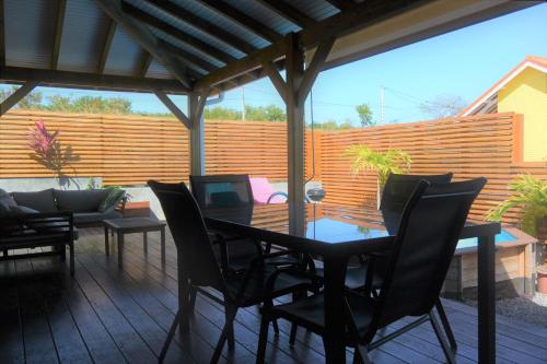 eine Terrasse mit einem Tisch, Stühlen und einem Zaun in der Unterkunft Maison Piscine personnelle vue mer COSY in Le Marin