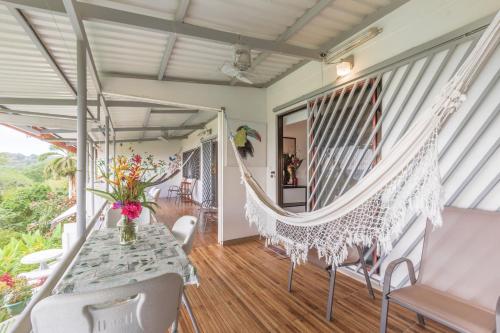 a porch with a hammock and a table and chairs at Hotel Villas de la Selva in Manuel Antonio