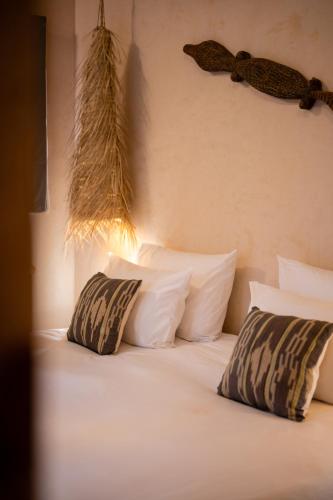 a bed with white pillows and aisal at Mama Lova Hôtel, Riad, Restaurant & Spa in Essaouira