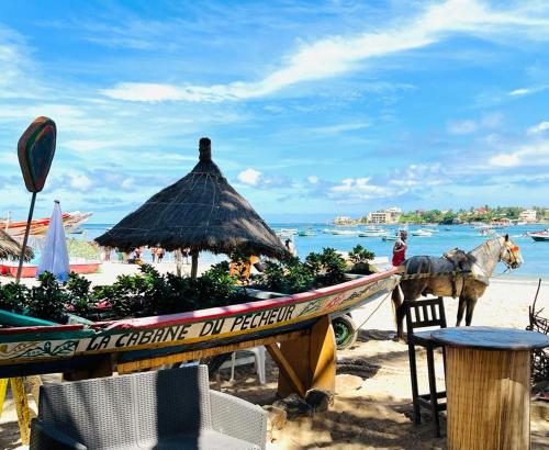 koń stojący obok łodzi na plaży w obiekcie La Cabane du Pêcheur Atlantic Evasion w mieście Dakar